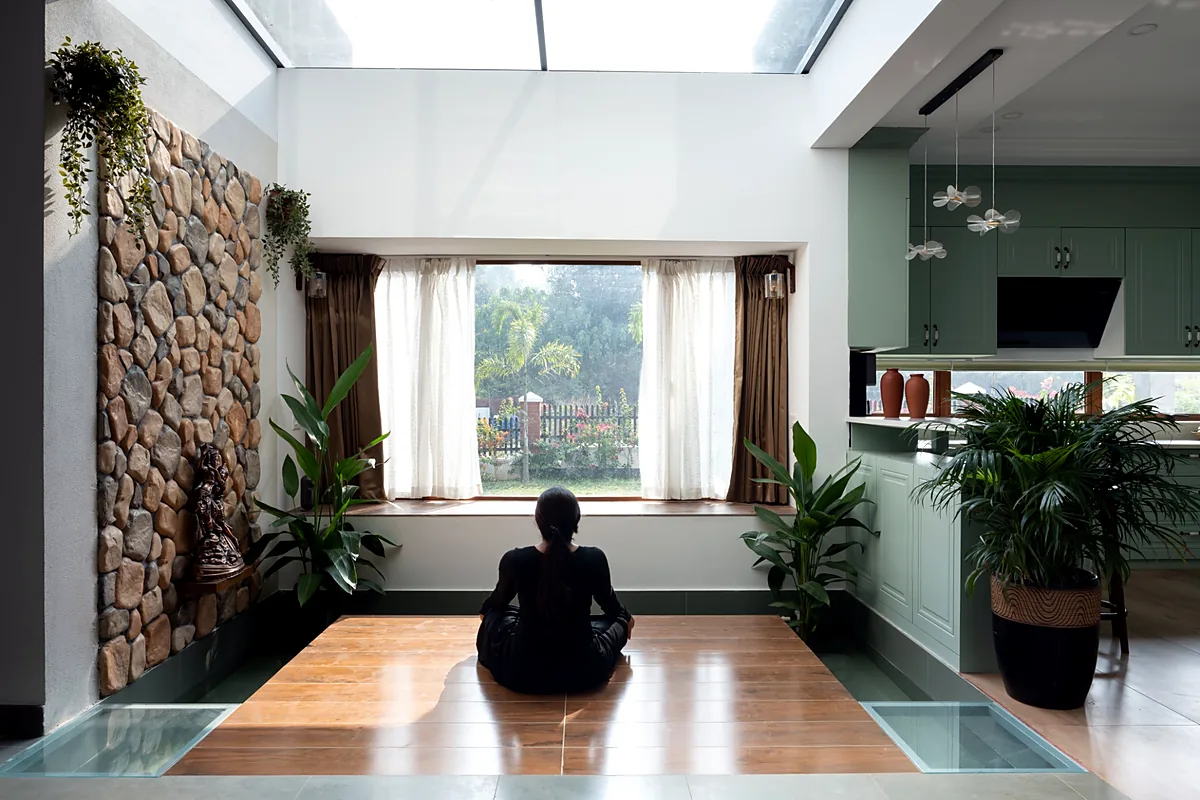 Skylit courtyard space with a stone wall, wooden flooring and a garden window in Casa Kanavu, a modern tropical home in Kerala
